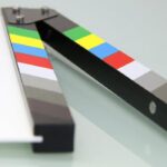 Colorful clapper board on a white surface, used in filmmaking. Ideal for entertainment and movie themes.